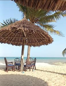 - un groupe de chaises sous un parasol sur la plage dans l'établissement Marieella homes, à Ukunda