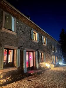 a stone building with doors and windows at night at Lerefugedetiti in Buissard