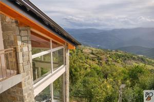 uma janela de uma casa com montanhas ao fundo em Xhaferri Guesthouse em Zhaban