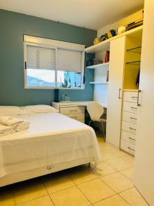 1 dormitorio con cama, escritorio y ventana en Apartamento aconchegante em Floripa - caminho das praias, en Florianópolis