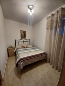 een kleine slaapkamer met een bed en gordijnen bij Casa Diego. Algodonales (Cadiz) in Algodonales