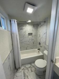 a white bathroom with a toilet and a bath tub at Travel Inn Motel in Anaheim