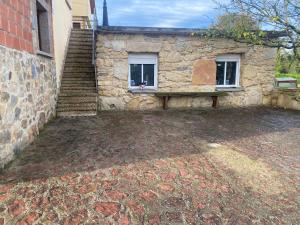 un edificio de piedra con un banco junto a una escalera en Alojamiento Finca La Campa 