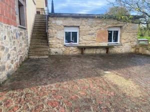 a stone building with a bench next to a stairs at Alojamiento Finca La Campa in Mareo de Abajo