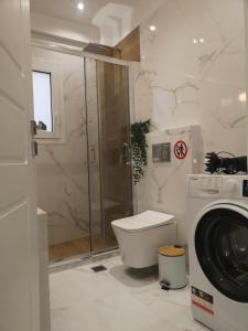 y baño con ducha y lavadora. en Athenian Luxury apartment, near metro station Chalandri, Nu 1, en Atenas