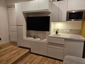 a kitchen with white cabinets and a flat screen tv at Parlement - Beau Studio in Rennes