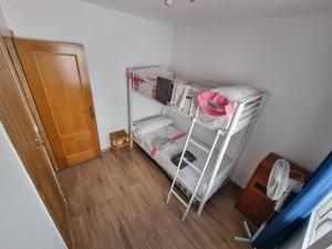 Habitación con litera blanca en una habitación en Casa Tranquila cerca del Mar en Santiago de la Ribera