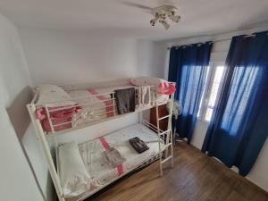 ein kleines Zimmer mit einem Etagenbett mit Kleidung in der Unterkunft Casa Tranquila cerca del Mar in Santiago de la Ribera