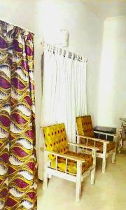 a room with two chairs and a window with curtains at Lalasalama B&B in Watamu