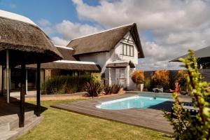 a house with a swimming pool and a thatch roof at CANAL GUEST HOUSE - Waterfront Boutique B&B in St Francis Bay