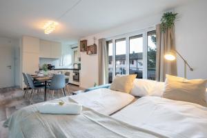 uma sala de estar com uma cama branca e uma cozinha em Moderne Wohnung mit Parkplatz - Top Floor em Ostermundigen