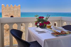 a table with a plate of food and a view of the ocean at Palais du Calife Riad Spa & Clubbing in Tangier