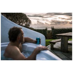Ein Mann, der in einer Badewanne mit einem Drink sitzt. in der Unterkunft Swn Y Don in Haverfordwest