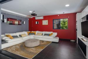a living room with a white couch and a red wall at Villa Galba in Le Gosier