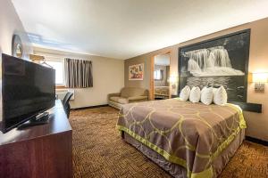 a hotel room with a bed and a flat screen tv at Super 8 by Wyndham Indianapolis Emerson in Indianapolis