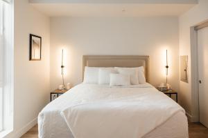 ein Schlafzimmer mit einem großen weißen Bett mit zwei Lampen in der Unterkunft Elegant Apartment in the Heart of Hollywood in Los Angeles