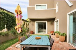 een patio met een blauwe tafel voor een huis bij Easy living West Beach family home in Kaapstad