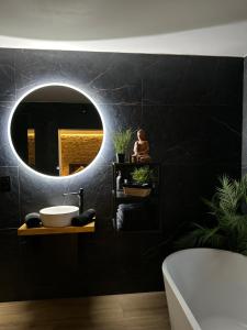 a bathroom with a black wall with a round mirror at Suite Tino in Verviers