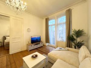 a living room with a couch and a tv at IDEE Living: Traumhaftes Altbau Apartment - Balkon in Wiesbaden