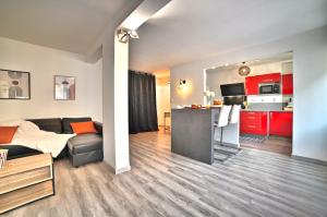 a room with a bed and a kitchen with red cabinets at Dolce Vita - Hypercentre - TV 4K - Fibre - Netflix in Saintes