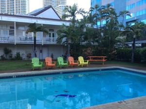 una piscina con sillas coloridas y una mesa en By the Beach Waikiki Heritage Hotel Honalulu, en Honolulu
