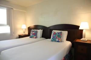 2 camas en una habitación de hotel con 2 lámparas en By the Beach Waikiki Heritage Hotel Honalulu, en Honolulu