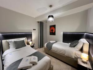 Spacious City Paradise - 3BR Apt in the Heart of Tirana في تيرانا: غرفة نوم بسريرين واضاءة قلادة