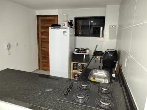 a kitchen with a stove and a white refrigerator at Residence Unno - Carapibús - PB / O paraíso que você procura esta aqui. in Jacumã