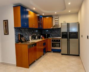 Spacious City Paradise - 3BR Apt in the Heart of Tirana في تيرانا: مطبخ مع خزائن خشبية وثلاجة من الفولاذ المقاوم للصدأ