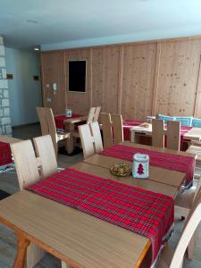 a dining room with wooden tables and chairs and a television at Agritur Maso Flonkeri in Bosentino