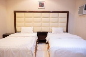 two beds in a room with white sheets at Ru'a Al Qunfudhah Furnished Units in Al Qunfudhah