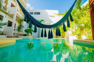 a swimming pool with a hammock in front of a building at Hotel San Vicente in Playa del Carmen