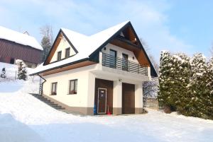 une maison avec un toit enneigé dans la neige dans l'établissement Apartament Pod Brzyzkiem, à Leśnica