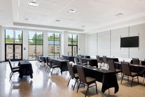 a conference room with tables and chairs and a flat screen tv at NOUN Hotel, Norman, a Tribute Portfolio Hotel in Norman