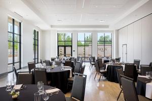 a dining room with tables and chairs and windows at NOUN Hotel, Norman, a Tribute Portfolio Hotel in Norman