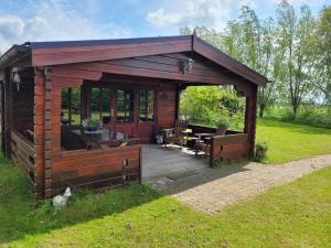 a wooden cabin with a wooden deck in the grass at Op e Mieden in Bartlehiem