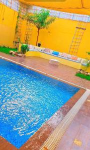 een zwembad met blauw water voor een gele muur bij شاليهات الدرب منتجع ليله in Qarār