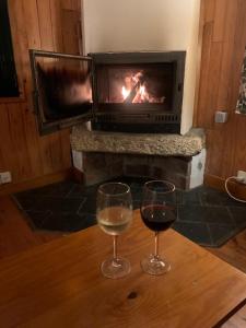 dois copos de vinho numa mesa em frente a uma lareira em Casa con encanto en Muros, Esteiro em Solleiros