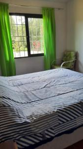 a bedroom with a bed with green curtains and a window at Casa de campo in Villarrica