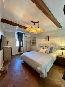 Un dormitorio con una gran cama blanca y una lámpara de araña. en La Saint-Pauloise en Saint-Paul-de-Vence