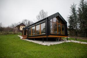 una casa negra con ventanas de cristal en un campo verde en Pelsonius Vendégház en Cserszegtomaj