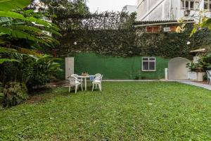 una mesa y sillas frente a una pared verde en Studio Gávea - Natureza, conforto e calmaria, en Río de Janeiro
