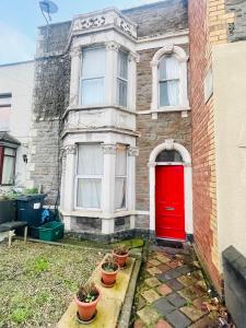 uma porta vermelha numa casa de tijolos com vasos de plantas em Mia Property - Two Mile Hill em Bristol