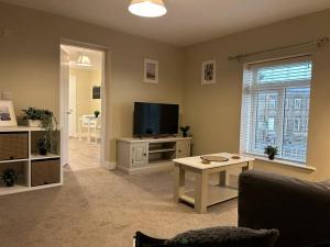 a living room with a couch and a television at Modern Relaxing Apartment in Stoke on Trent