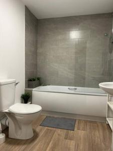 a bathroom with a tub and a toilet and a sink at Modern Relaxing Apartment in Stoke on Trent