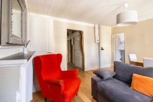 - un salon avec une chaise rouge et un canapé dans l'établissement PARLEMENT 2 - 55m2 -2 CH et 2 SDE, à Rennes