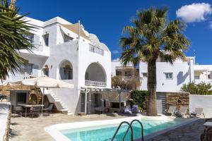 a villa with a swimming pool and a palm tree at Onar Hotel & Suites in Tinos