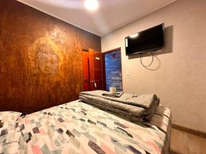 a bedroom with a bed and a tv on the wall at Hotel Patahuasi in Pucusana