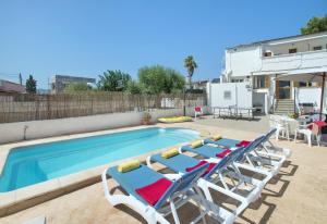 einen Pool mit 2 Liegestühlen und einem Pool in der Unterkunft Owl Booking Villa Trinxater - 12 Min Walk to the Beach in Alcúdia