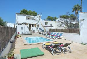 einen Hinterhof mit Pool und Stühlen und ein Haus in der Unterkunft Owl Booking Villa Trinxater - 12 Min Walk to the Beach in Alcúdia